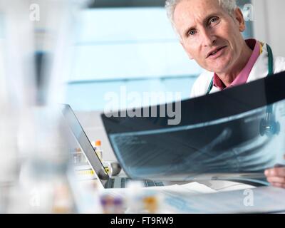 EIGENTUM FREIGEGEBEN. -MODELL VERÖFFENTLICHT. Arzt eine Röntgenaufnahme einer gebrochenen Hand in einem Krankenhaus anzeigen. Stockfoto