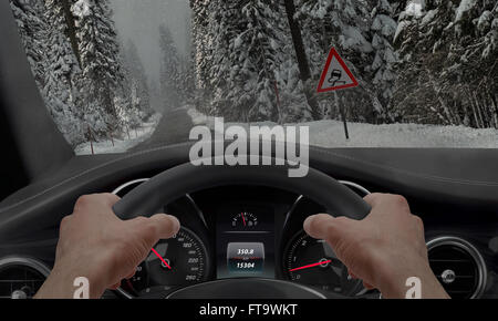 Auto auf einer Straße im Schnee Eis rutschen. Am Wegesrand ist ein Zeichen für rutschige Straße. Stockfoto