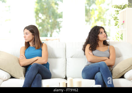 Zwei böse Freunde nach einem Streit auf einer Couch sitzend und mit Blick auf die andere Seite Stockfoto