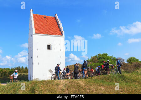 Junge Menschen auf dem Fahrrad zu Sand bedeckten Kirche in Skagen Stockfoto