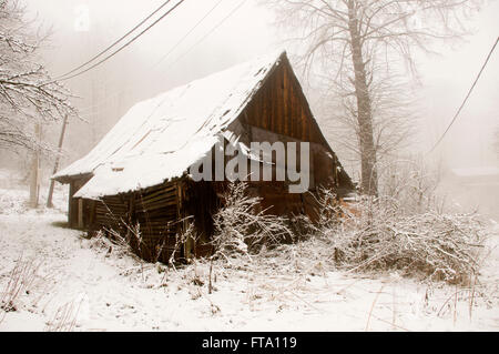 Das alte Holzhaus mit weiß Schnee bedeckt Stockfoto