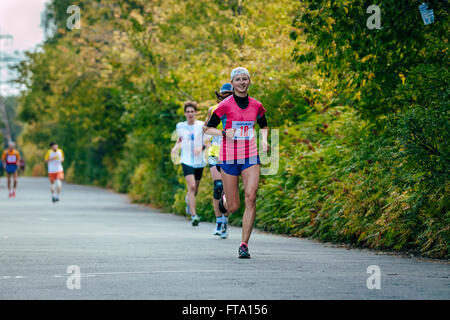 junge Mädchen lächelt läuft auf Straßenseite im Park während Chelyabinsk marathon Stockfoto