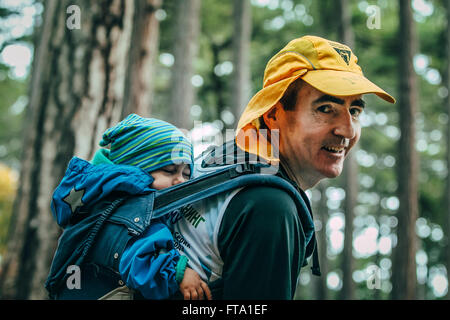 Nahaufnahme der Vater trägt sein Kind auf dem Rücken in einem Rucksack während Bergmarathon Stockfoto