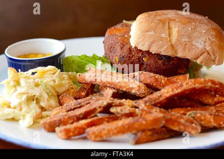 Pflanzlichen Burger in einem Brötchen mit Süßkartoffel Pommes, Krautsalat und Relish Stockfoto
