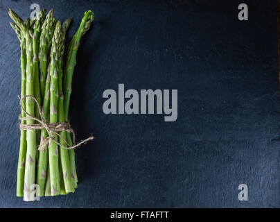 Grüner Spargel (Nahaufnahme) auf eine Schiefer-Tafel (Tiefenschärfe) Stockfoto