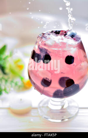 Cocktail in ein Glas mit Beeren und Wasser spritzt Stockfoto