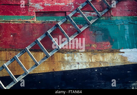 Holzleiter gegen farbige Rumpf ein altes Holzschiff in Bretagne, Frankreich bei Ebbe Stockfoto