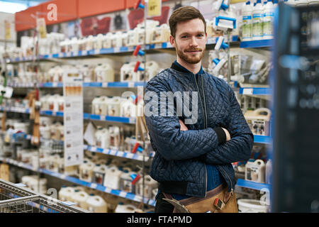 Zuversichtlich Heimwerker im Baumarkt Ansehen unter den Regalen von Produkten mit verschränkten Armen in die Kamera lächeln Stockfoto