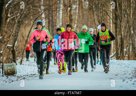 Jekaterinburg, Russland - 14. November 2015: Gruppe Sportler Männer und Frauen in hellen Winterkleidung läuft auf verschneiten Weg Park Stockfoto