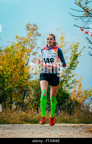 Mädchen unterwegs im herbstlichen Wald in Kompressionsstrümpfe und Kinesio Tape auf Knien laufen Stockfoto