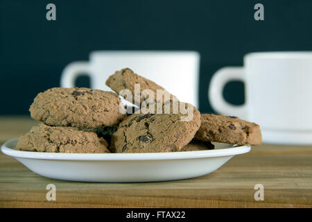Schokoladen-Cookies und zwei Tassen Tee auf einem Holztisch Stockfoto