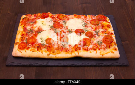 Pizza auf Platte Schiefer auf Holztisch Stockfoto