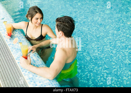 Junges Paar mit Getränke im Pool entspannen Stockfoto