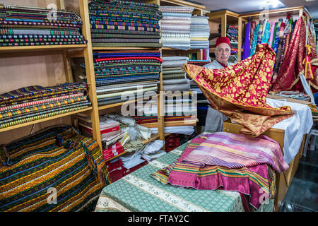 Bilal Abu Khalaf, Händler von importierten orientalischen Stoffen zeigt Textilien in seinem Geschäft auf einem Markt auf der alten Stadt von Jerusalem, Israel Stockfoto