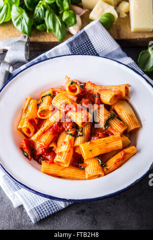 Nudeln. Italienische und mediterrane Küche. Pasta Rigatoni mit Tomaten-Sauce Basilikum Blätter Knoblauch und Parmesan-Käse. Ein altes Haus Stockfoto