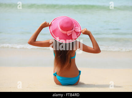 Frau in großen Hut sitzt am Strand am Meer Stockfoto