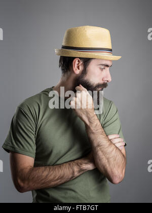 Profil Ansicht von traurig bärtigen Mann mit Strohhut wegsehen. Kopfschuss-Porträt über graue Studio-Hintergrund mit Vignette. Stockfoto