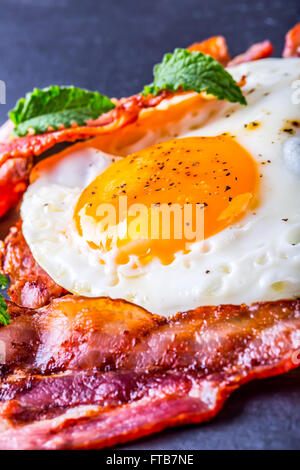 Schinken und Ei. Speck und Ei. Ei gesalzen und mit schwarzem Pfeffer bestreut. Englisches Frühstück. Stockfoto