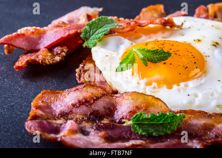 Schinken und Ei. Speck und Ei. Ei gesalzen und mit schwarzem Pfeffer bestreut. Englisches Frühstück. Stockfoto