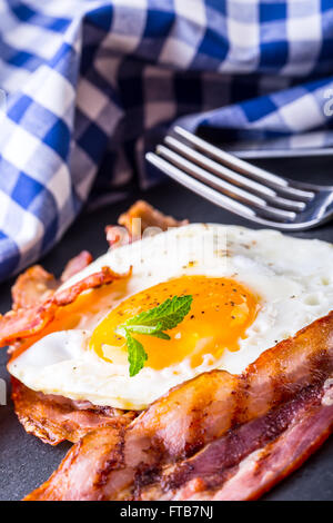 Schinken und Ei. Speck und Ei. Ei gesalzen und mit schwarzem Pfeffer bestreut. Englisches Frühstück. Stockfoto