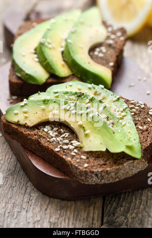 Toast mit Avocado und Gewürze, Sesam auf einem hölzernen Hintergrund Stockfoto