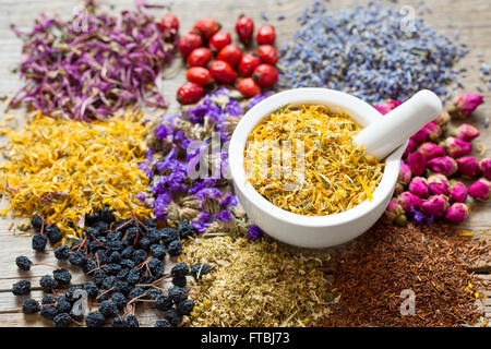 Mörtel von trockenen Ringelblume Blumen, Kräuter Tee Sortiment und Beeren auf Tisch. Die Kräutermedizin. Stockfoto