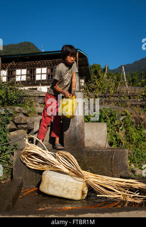 Mädchen holen Wasser aus einem Hahn Gemeinschaft in Nabji Dorf, Süd-Bhutan Stockfoto