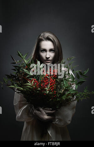 Dunkle Porträt einer schönen blasse Frau mit roten Blumen. Vampir Stockfoto