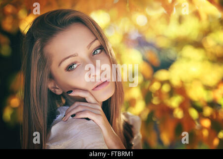 Warme Herbst-Porträt einer jungen Frau. Goldene Blätter hinter Stockfoto