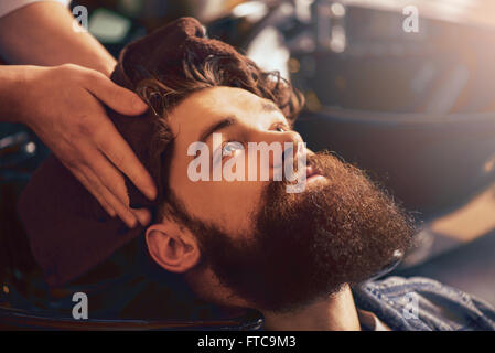 professionelle Friseur Kopf seines Mandanten mit Handtuch trocknen Stockfoto