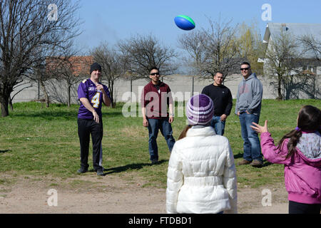 150410-N-TQ904-105 DEVESELU, Rumänien (10. April 2015) Waffenwart 2. Klasse Dustin Kearney wirft einen Fußball mit einer rumänischen Mädchen in Deveselu-Schule in Rumänien, 10. April 2015. Kearney aus Raleigh, North Carolina und anderen Seglern aus dem nahe gelegenen Aegis an Land base, verbrachte den Vormittag Unterricht der rumänischen Kinder über US Osterbräuche und Sport. Naval Support Facility Deveselu hat eine andauernde Beziehung mit Deveselu Schule, die wird umgebaut und erweitert durch die Marine Anlagen-Engineering-Kommando. (Foto: U.S. Navy Lt. CMdR Mike Billips/freigegeben) Stockfoto