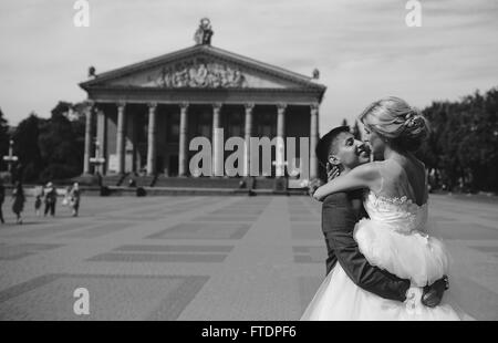 Bräutigam hält Braut im Arm und verdreht Stockfoto