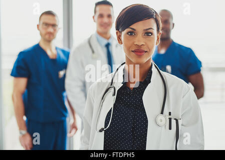 Zuversichtlich Ärztin vor Team, blickte lächelnd, multirassische Kamerateam mit schwarz Ärztin Stockfoto