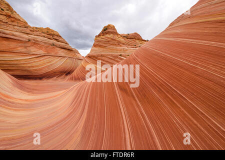 Rote Wellen - bunt und wirbelnden Sandstein, unter einem stürmischen und bewölkten Himmel bei The Wave, nahe der Grenze zu Arizona-Utah, USA. Stockfoto