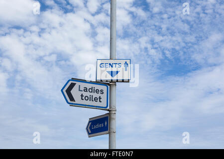 Anzeichen auf einen Pfahl oder Pfosten zeigen, wohin die nächste Publica Toiletten WC oder Ruheraum für Männer und Frauen. Stockfoto