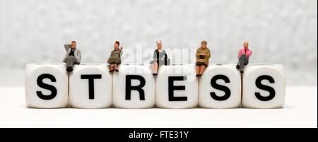 Miniatur-Figuren sitzen oben auf das Wort stress Stockfoto