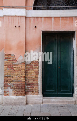 Fassade Detail eines verfallenden Gebäudes mit bröckelnden rosa gemalt machen ausgesetzt warm getönten roten und orangen Mauerwerk in Venedig, Italien Stockfoto