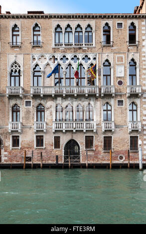 Klassisches Hafengebäude mit verzierten Fenstern und Balkonen mit Anlegestellen und einer Anlegestelle am Canale Grande, Venedig, Italien Stockfoto