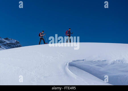 Zwei männliche Schneeschuhwanderer an einem sonnigen Wintertag in den Schweizer Alpen wandern. Melchsee-Frutt, Kanton Obwalden, Schweiz. Stockfoto