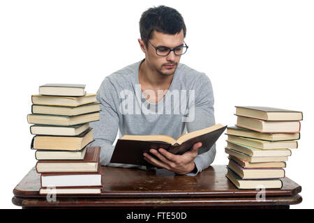Junger Mann in Gläsern liest Buch am Tisch Stockfoto