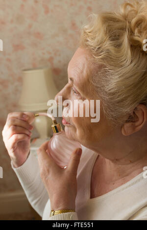 Ältere Dame Parfüm aus einer alten altmodische rosa Glas-Flasche anwenden. Stockfoto
