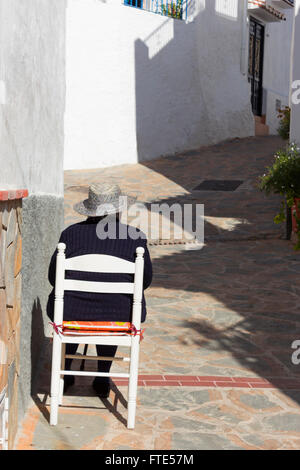 Rückansicht der spanische Dame saß auf einem Stuhl vor ihrem Haus in dem Dorf Totalan, Málaga, Südspanien. Stockfoto