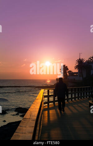 La Cala de Mijas Costa Del Sol, Malaga, Spanien.  Silhouette der Mann ging bei Sonnenuntergang an der Strandpromenade. Stockfoto