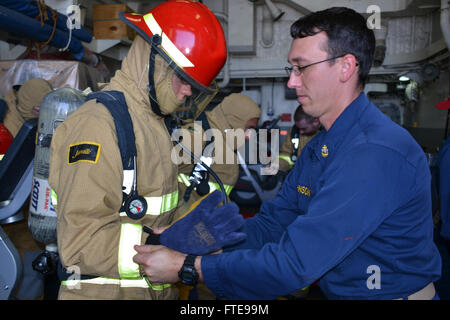 140127-N-ZZ999-001 indischen Ozean - (26. Januar 2014) - Chief Boatswain Mate Justin Johnson unterstützt eine Kerl Sailor Kleid heraus in seinem Ensemble zur Brandbekämpfung während der Schadensbegrenzung Training Evolution an Bord der Arleigh-Burke-Klasse geführte Flugkörper Zerstörer USS Nitze (DDG-94). Nitze ist auf eine geplante Bereitstellung unterstützen maritimer Sicherheitsoperationen und Sicherheitsbemühungen Zusammenarbeit Theater in den USA 6. Flotte Einsatzgebiet. (Foto: US-Marine Gunner es Mate Seaman Naquon Kebe) Nehmen Sie das Gespräch auf Twitter (https://twitter.com/naveur navaf) folgen Sie uns auf Facebook (https://www.facebook.com/ Stockfoto