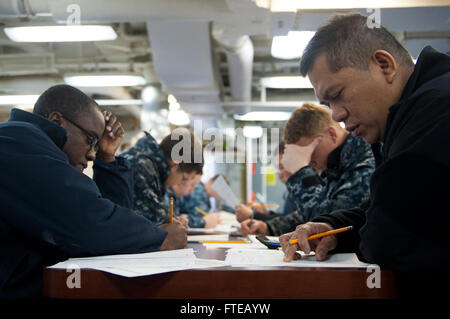 Am 6. März 2014 nehmen an Bord der USS Arleigh Burke (DDG 51) in Marseille, Frankreich, der Culinary Specialist 2nd Class Wilson Bohol und der Boatswain's Mate 2nd Class Orane Allen die 1st Class Petty Officer-Aufstiegsprüfung der Marine auf den Schiffsdecks ab. Stockfoto