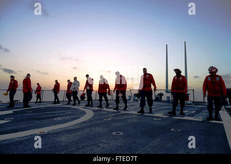 Das Bild zeigt Seeleute an Bord der USS Ramage (DDG 61), einem Raketenzerstörer der Arleigh-Burke-Klasse, die eine Routinewartung auf dem Flugdeck durchführen, um sich auf den Flugbetrieb vorzubereiten. Die USS Ramage wurde im Mittelmeer eingesetzt und unterstützte die Operationen der 6. US-Flotte. Stockfoto