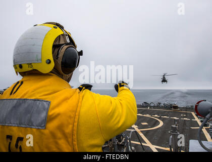 Dieses Bild zeigt Boatswains Mate 2nd Class Antavius Zachery auf der USS Donald Cook (DDG 75), der während einer Operation im Schwarzen Meer einen Hubschrauber der rumänischen Marine IAR 330 Puma signalisiert. Die USS Donald Cook ist ein Lenkraketenzerstörer der Arleigh-Burke-Klasse, der an NATO-Operationen beteiligt ist. Stockfoto