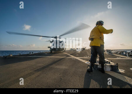 Dieses Bild zeigt die USS *Donald Cook* (DDG 75), einen Raketenzerstörer der Arleigh-Burke-Klasse, der Operationen im Mittelmeer durchführt. Das Foto zeigt Boatswains Mate 2nd Class Antavius Zachery, der einen SH-60B Seahawk Hubschrauber auf dem Flugdeck des Zerstörers signalisiert. Die USS *Donald Cook* wird im Rahmen der europäischen Verteidigungsstrategie der USA nach Rota, Spanien, eingesetzt. Stockfoto
