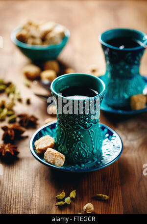 Tee oder Glühwein oder andere Getränke mit verschiedenen Gewürzen in traditionellen türkischen Gläser auf hölzernen Hintergrund. Selektiven Fokus. Stockfoto