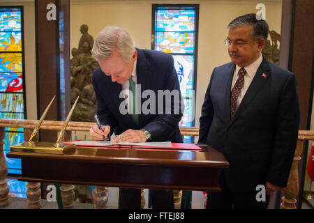 ANKARA, Türkei (12. November 2014) Secretary Of The Navy (SECNAV) Ray Mabus unterschreibt das Gast-Protokoll an das Ministry of Defense, wie dem türkischen Minister für Verteidigung Ismet Yilmaz blickt auf. Mabus traf Yilmaz und andere Führer der türkischen Abteilung der marinen Beziehungen zwischen den beiden Ländern zu diskutieren. Stockfoto